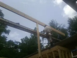 Carpenter setting a ridge beam over a new addition frame — Ice Dam Removal by Roofing Brothers in Gleneden Beach