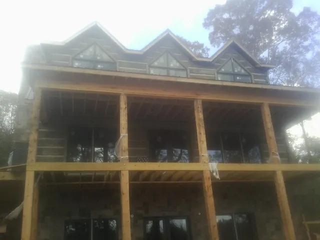 Dormers and porch framing on a large log home under construction — Roof Coating work by our crew in Gleneden Beach