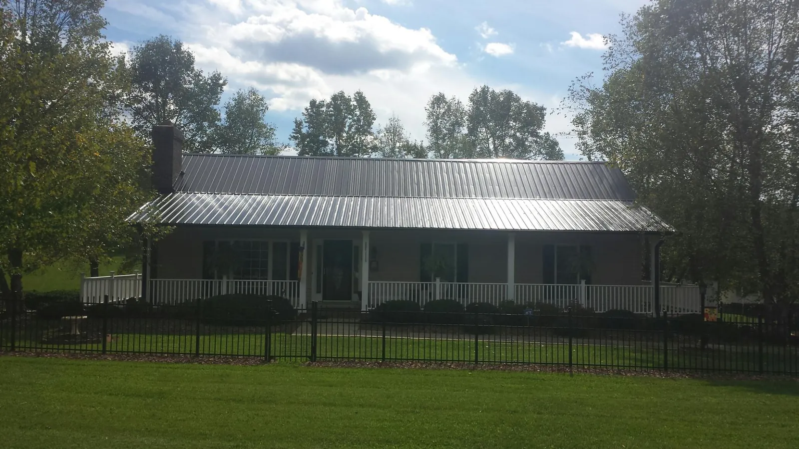 Gray metal roof on a brick ranch with a full width front porch — Gutter Guard Installation work by our crew in Gleneden Beach
