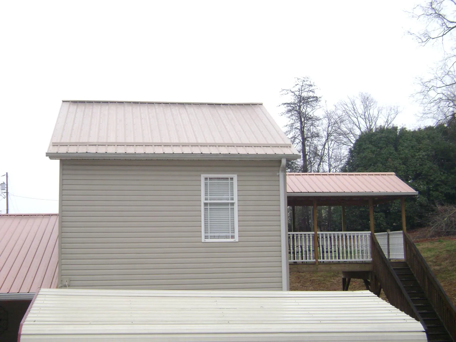 Tan metal roofs on a two story addition and attached porch, from a Roof Replacement job in Gleneden Beach
