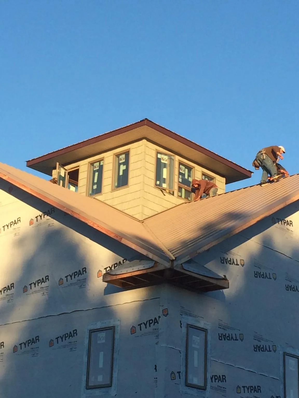 Roofers working around a rooftop cupola on a new metal roof at sunset — Roof Waterproofing in Gleneden Beach by Roofing Brothers